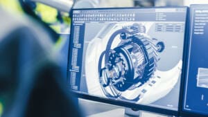At the Factory: Female Mechanical Engineer Designs 3D Engine on Her Personal Computer while Male Automation Engineer Uses Laptop for Programming Robotic Arm.